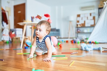 Adorable toddler playing around lots of toys at kindergarten