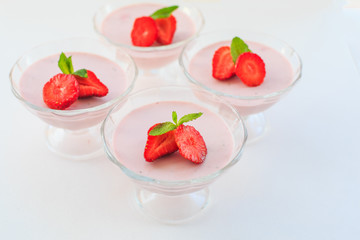 delicate strawberry ice cream with slices of strawberries with cream in a glass bowl on a light background, for advertising confectioners or sweets