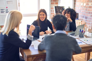 Group of business workers smiling happy and confident. Working together with smile on face  using laptop and speaking at the office