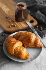 Two croissants with chocolate paste and nuts on a table