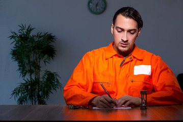 Young convict man sitting in dark room