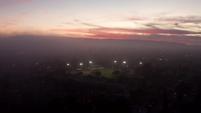 aerial view above the clouds during sunset towards a baseball field