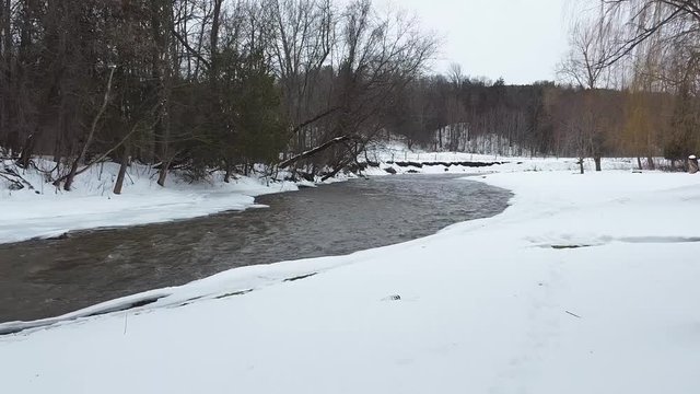 Fly drone threw trees river shot in winter
