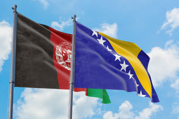 Bosnia Herzegovina and Afghanistan flags waving in the wind against white cloudy blue sky together. Diplomacy concept, international relations.