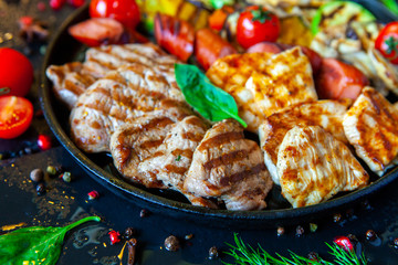 Assorted delicious grilled meat with vegetable. Mixed grilled bbq meat with vegetables. Beef, pork, poultry, sausages, grilled garlic, chili pepper, red tomatoes
