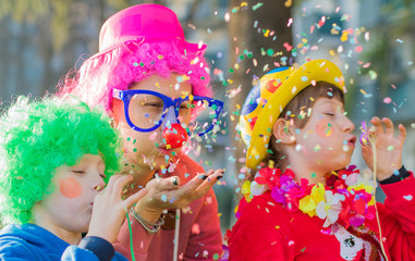 a mother and her children are playing with confetti in carnival costume - 320374416