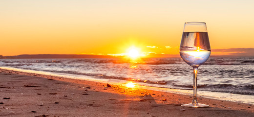 Reflet dans un verre au coucher du soleil sur une plage.