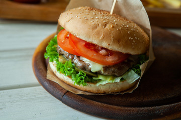 big tasty burger on a wooden table and french fries. Delicious burger with beef, tomato, cheese and lettuce.