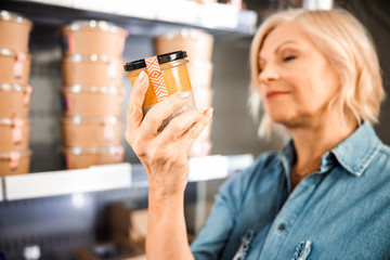 Smiling mature woman reading information on products in store