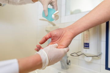 Nurse disinfects a patients hand at a sink