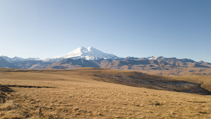 Fototapeta na wymiar Beautiful landscape: desert highlands in autumn. View of mount Elbrus. Dry grass, rocks, mountains. Trip to the Caucasus in Russia