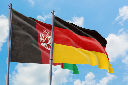 Germany and Afghanistan flags waving in the wind against white cloudy blue sky together. Diplomacy concept, international relations.