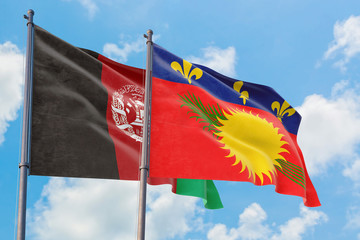 Guadeloupe and Afghanistan flags waving in the wind against white cloudy blue sky together. Diplomacy concept, international relations.