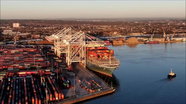 Busy container port with ship loading and unloading in dock. Aerial hyperlapse, time lapse showing cranes at work.