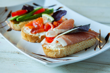 Appetizing bruschetta. Traditional Italian bruschetta. Open sandwich with salmon and vegetables. Delicious healthy food. European cuisine. 