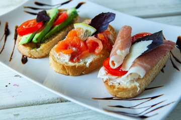 Appetizing bruschetta. Traditional Italian bruschetta. Open sandwich with salmon and vegetables. Delicious healthy food. European cuisine. 