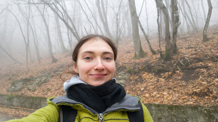 Autumn frame: a teenage traveler takes a selfie against a background of bald trees. A woman travels...