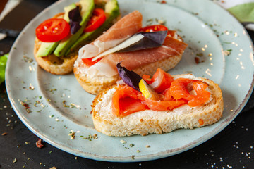 Appetizing bruschetta. Traditional Italian bruschetta. Open sandwich with salmon and vegetables. Delicious healthy food. European cuisine. 