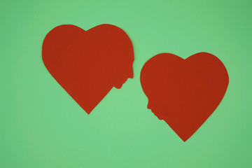 Two paper hearts with silhouettes of faces of woman and man on mint background. Love concept. Relationship concept.