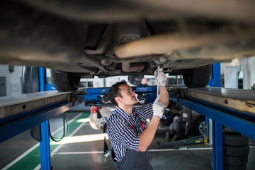 Male e Mechanis working underneath car together