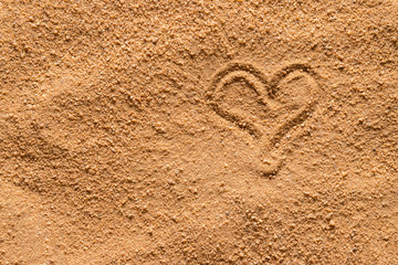 A heart is drawn on the surface of the sand.