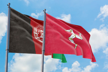 Isle Of Man and Afghanistan flags waving in the wind against white cloudy blue sky together....
