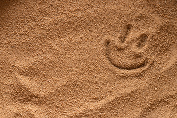 Fototapeta na wymiar A smiling smiley is painted on a sandy background.