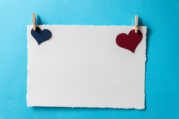Postcard template with burgundy and blue hearts and tiny clothespins on a blue background.