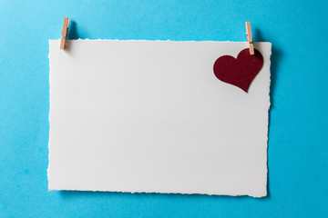 Postcard template with burgundy heart and tiny clothespins on a blue background.