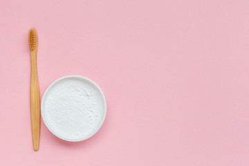 plastic less lifestyle, eco friendly tooth brush and natural powder toothpaste isolated on pastel pink background, flat layout, copy space