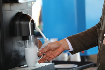 Fototapeta na wymiar Man is getting coffee from coffee machine