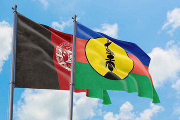 New Caledonia and Afghanistan flags waving in the wind against white cloudy blue sky together. Diplomacy concept, international relations.