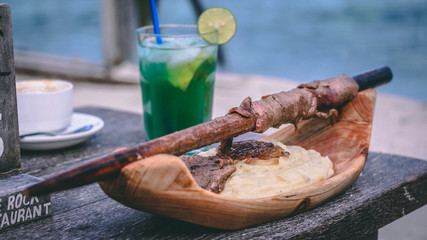 Pingwe, Zanzibar, Tanzania 30.12.2019 - Beef with potatoes in The Rock restaurant with a cocktail in the background