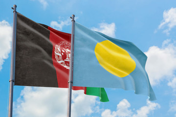 Palau and Afghanistan flags waving in the wind against white cloudy blue sky together. Diplomacy concept, international relations.