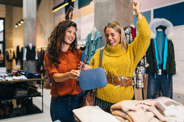 Female seller helps buyer to choose between diferent clothes.