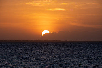 Sunset on a beach in Zanzibar. Sun hiding behind the clouds