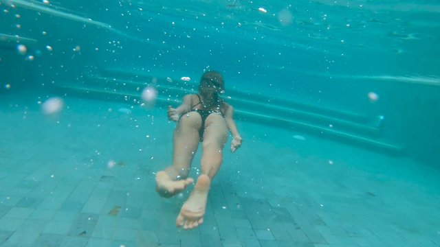4K Underwater footage of woman diving in the pool. Backview woman diving underwater.