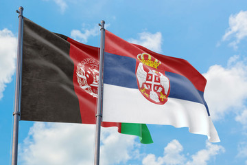 Serbia and Afghanistan flags waving in the wind against white cloudy blue sky together. Diplomacy concept, international relations.