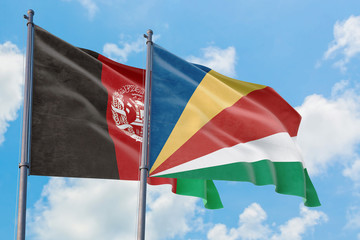 Seychelles and Afghanistan flags waving in the wind against white cloudy blue sky together. Diplomacy concept, international relations.