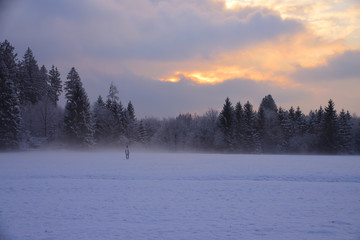Person in Schneegestöber bei Sonnenuntergang