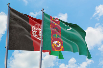 Turkmenistan and Afghanistan flags waving in the wind against white cloudy blue sky together. Diplomacy concept, international relations.