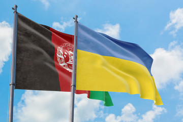 Ukraine and Afghanistan flags waving in the wind against white cloudy blue sky together. Diplomacy concept, international relations.