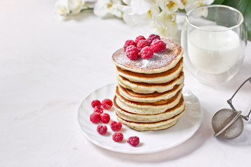 Healthy breakfast: stack of classic american pancakes with berries (raspberries) and milk. Copy space, white background