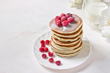 Healthy breakfast: stack of classic american pancakes with berries (raspberries) and milk. Copy space, white background