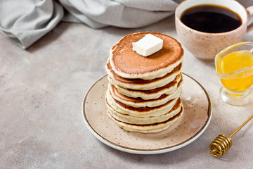 Healthy and delicious breakfast: coffee and stack of classic american pancakes with butter and honey. Copy space, gray background