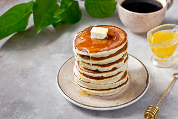 Healthy and delicious breakfast: coffee and stack of classic american pancakes with butter and honey. Gray background