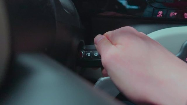 A close up view over the steering wheel of igniting the car by rotating car key.