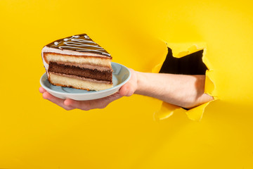 Hand holding a big piece of chocolate cake