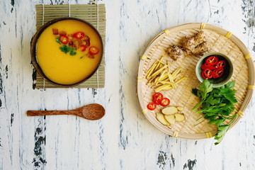 Freshly made creamy pumpkin soup served in coconut bowls with asian seasonings and pumpkin seeds