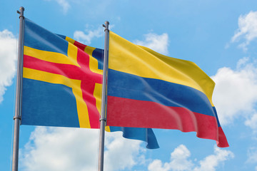 Colombia and Aland Islands flags waving in the wind against white cloudy blue sky together. Diplomacy concept, international relations.
